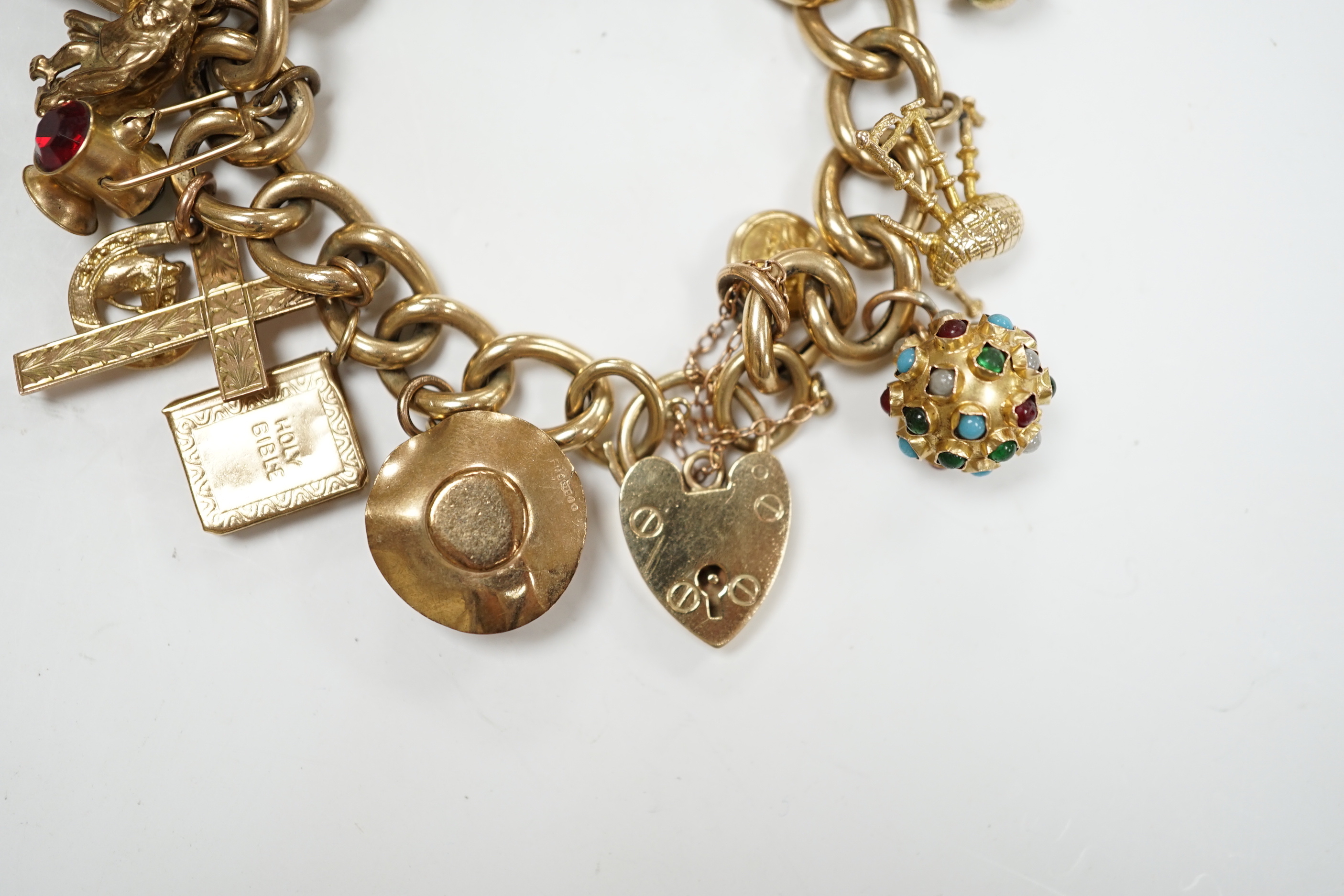 An early 1960's 9ct gold curb link charm bracelet, hung with fifteen assorted charms, including twelve 9ct gold, gross weight 49.7 grams.